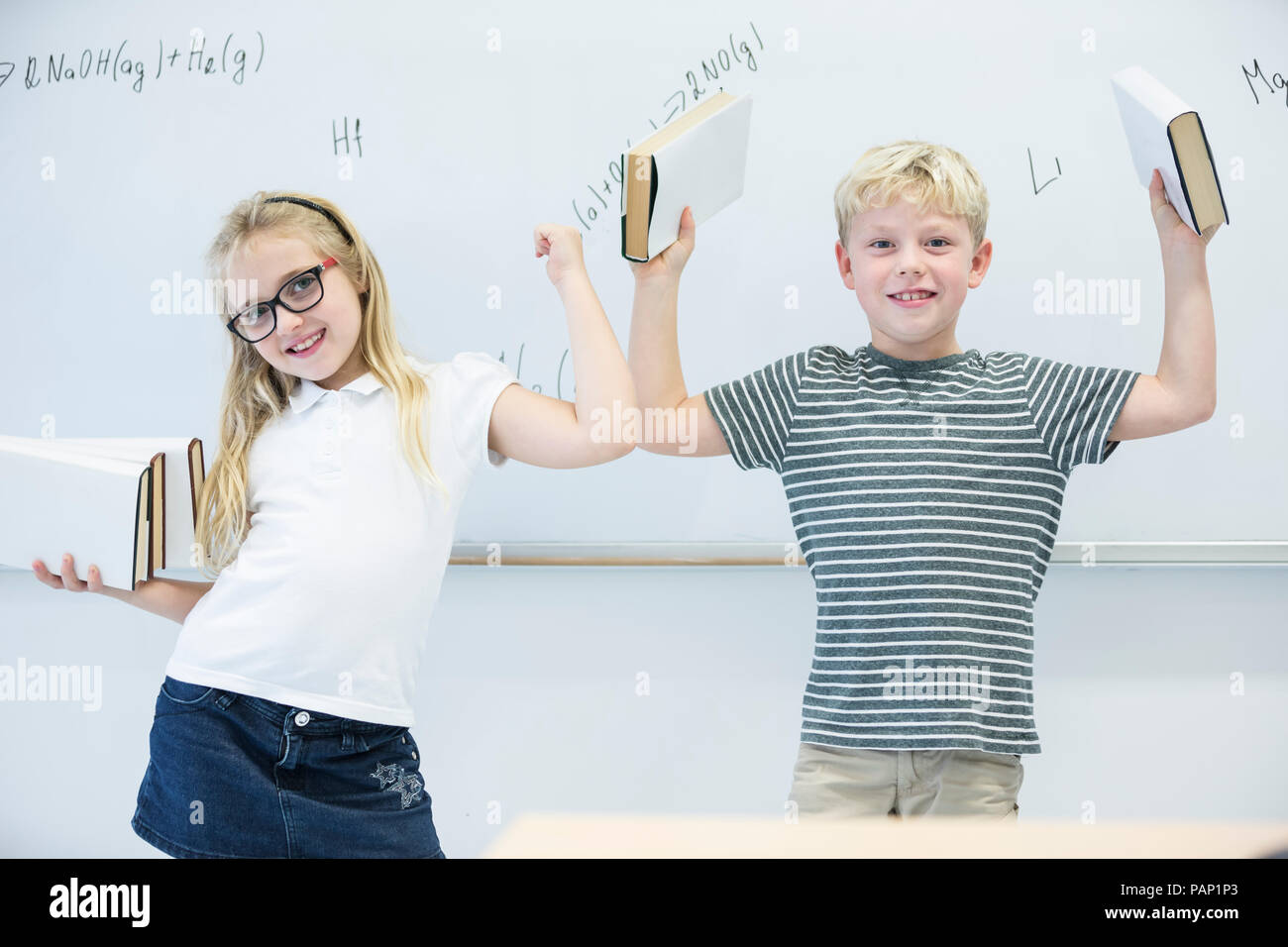 Ritratto di felice schoolgirl e schoolboy trasporto di libri in classe Foto Stock