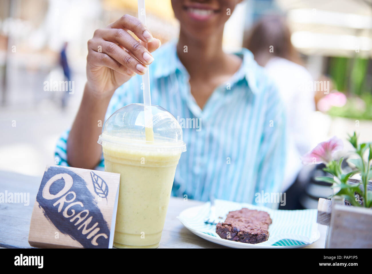 Donna bere frullato organico a Pavement Cafe, vista parziale Foto Stock