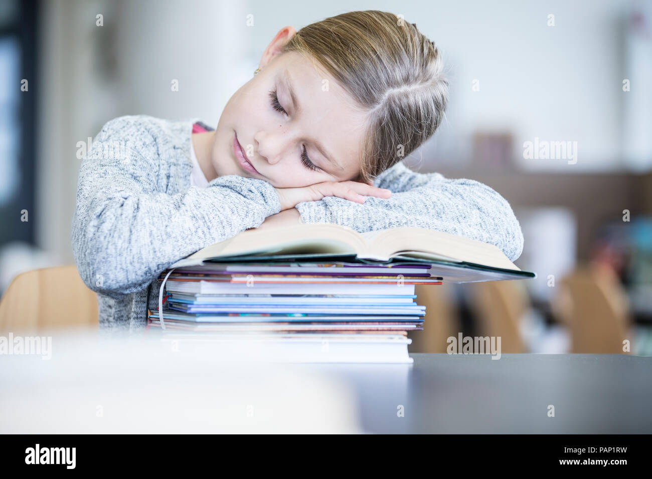 Da studentessa di dormire sulla pila di libri sul tavolo a scuola Foto Stock