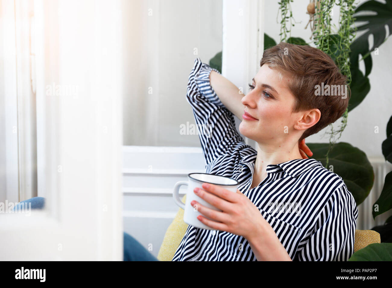 Felice donna seduta rilassante a finestra, a bere caffè Foto Stock