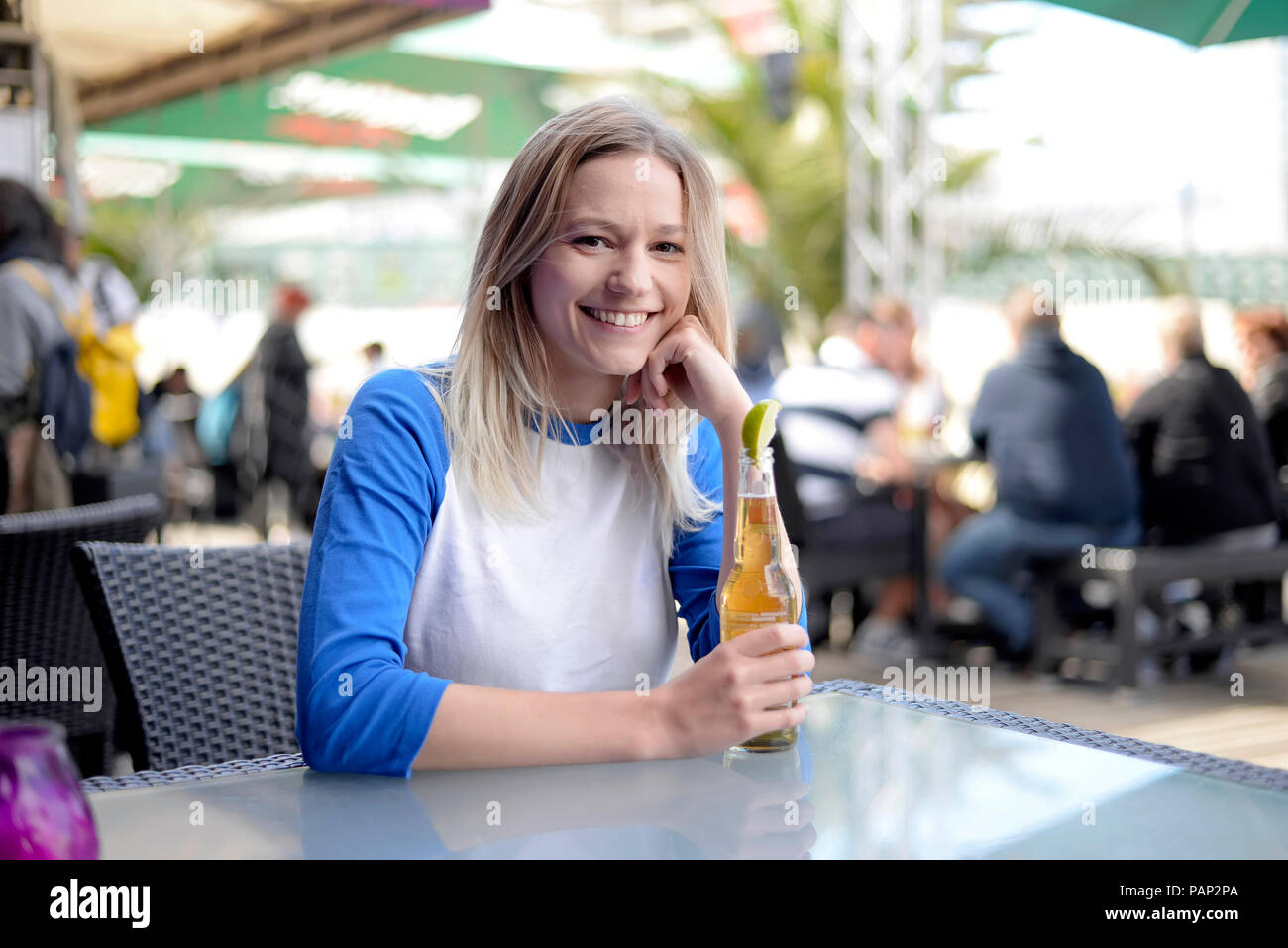 Giovane donna bionda con bottiglia di birra nel giardino della birra Foto Stock