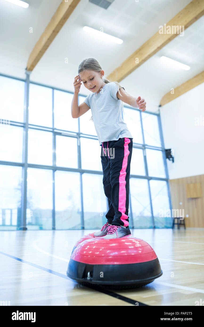 Schoolgirl equilibratura su attrezzature per esercizi in palestra di classe Foto Stock