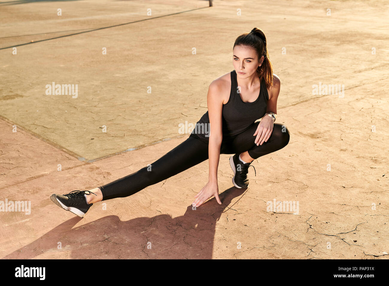 Donna sportive allungamento della gamba sul pavimento in calcestruzzo Foto Stock
