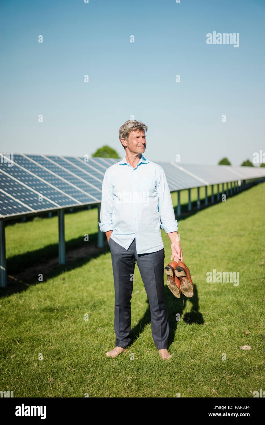 Uomo maturo a piedi nudi sul prato in impianto solare Foto Stock