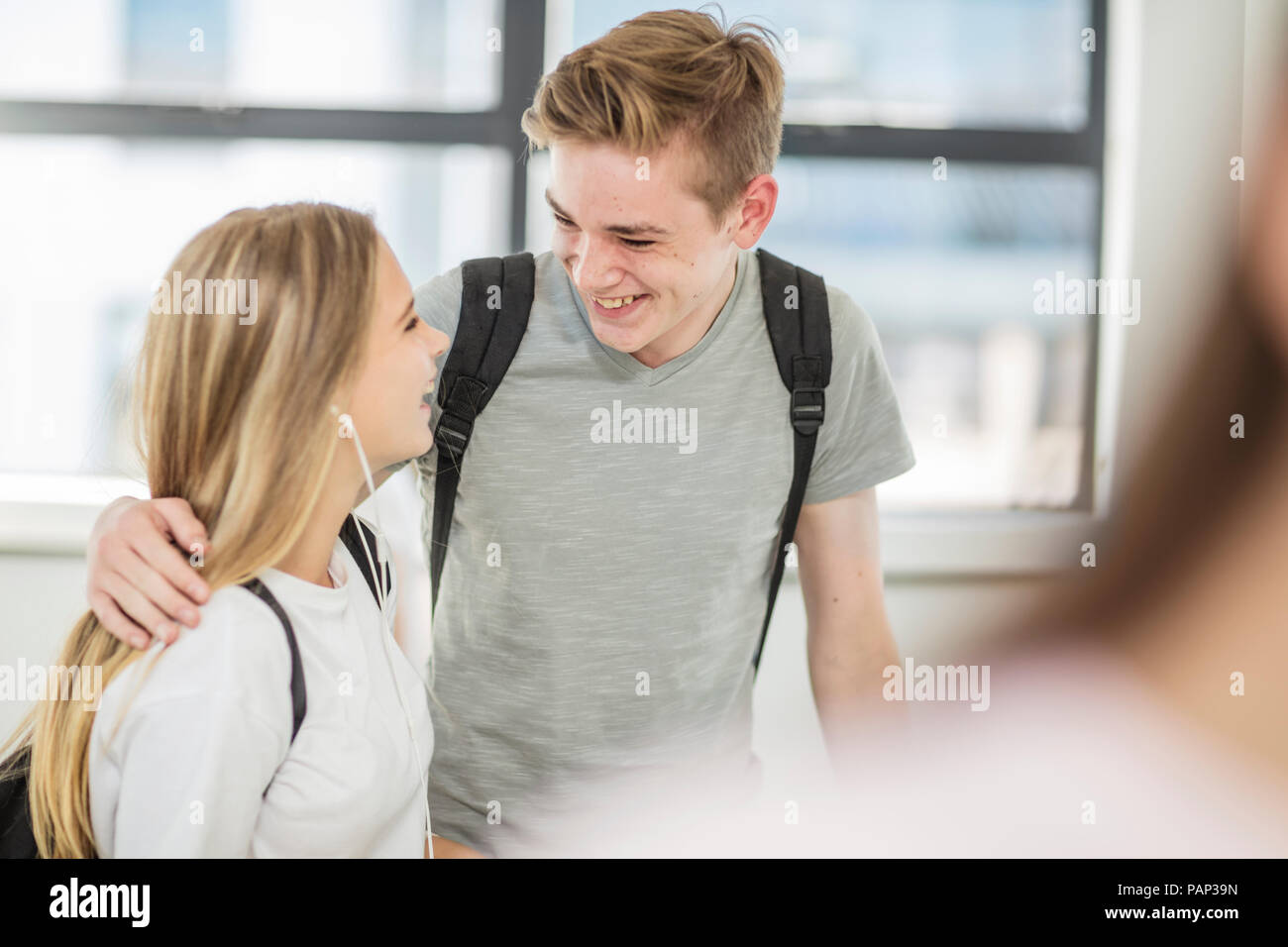 Ragazzo che sorride e abbracciando la ragazza a scuola Foto Stock