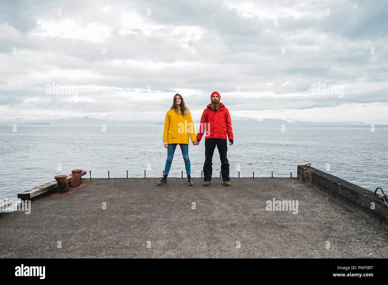 In Islanda, a nord di Islanda, coppia giovane in piedi mano nella mano sul molo Foto Stock