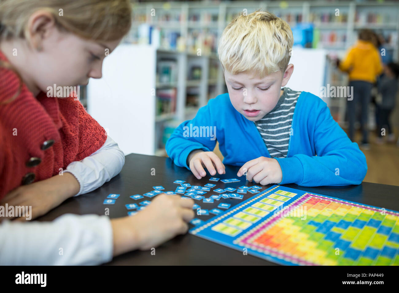 Gli alunni la riproduzione di un gioco di bordo nella biblioteca della scuola Foto Stock