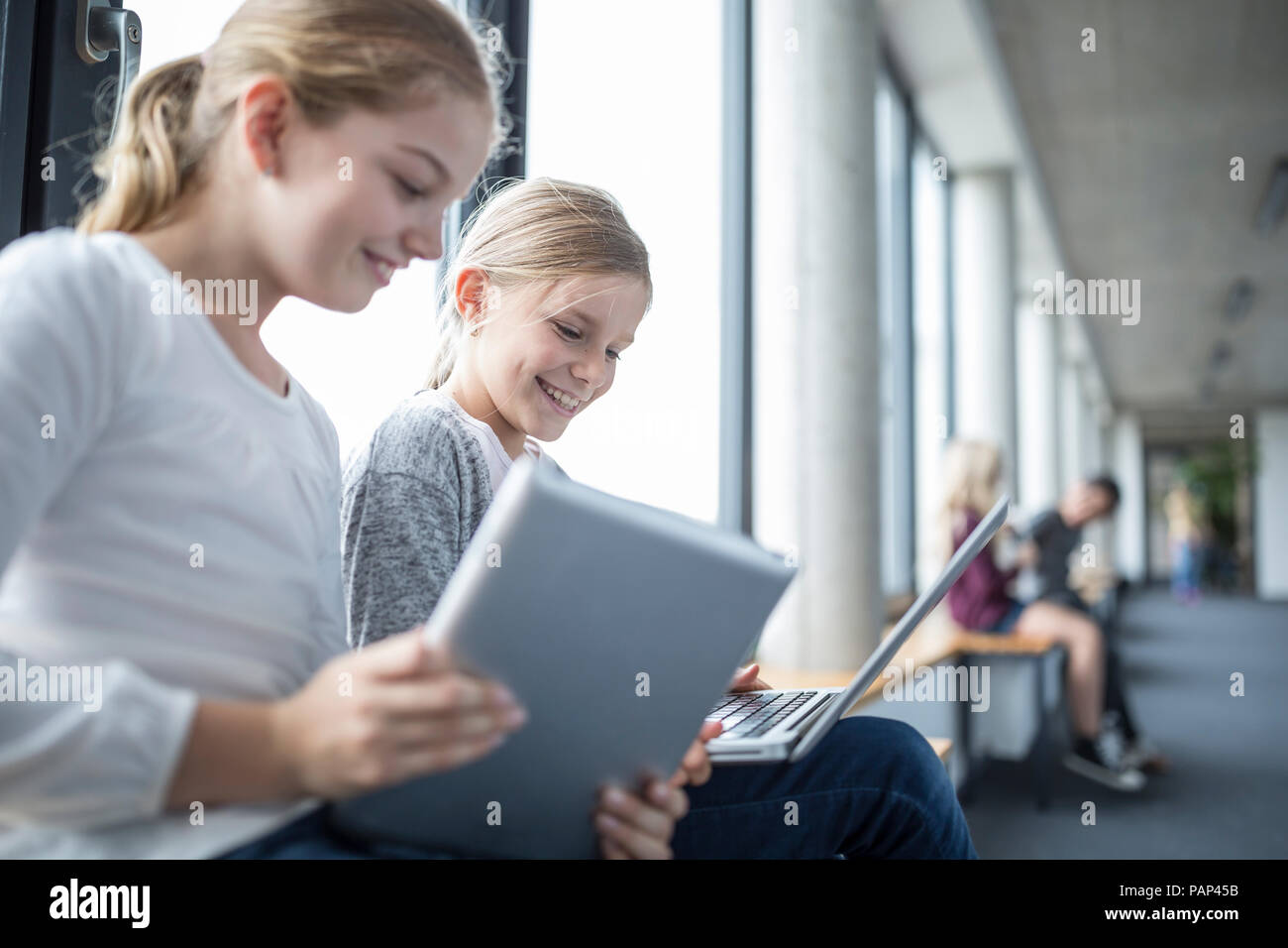 Felice studentesse con laptop e tablet sul corridoio di scuola Foto Stock