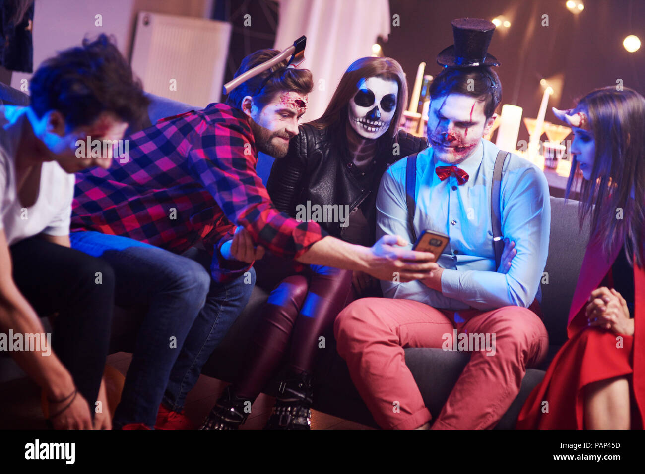 Gli amici utilizzando il telefono cellulare alla festa di Halloween Foto Stock