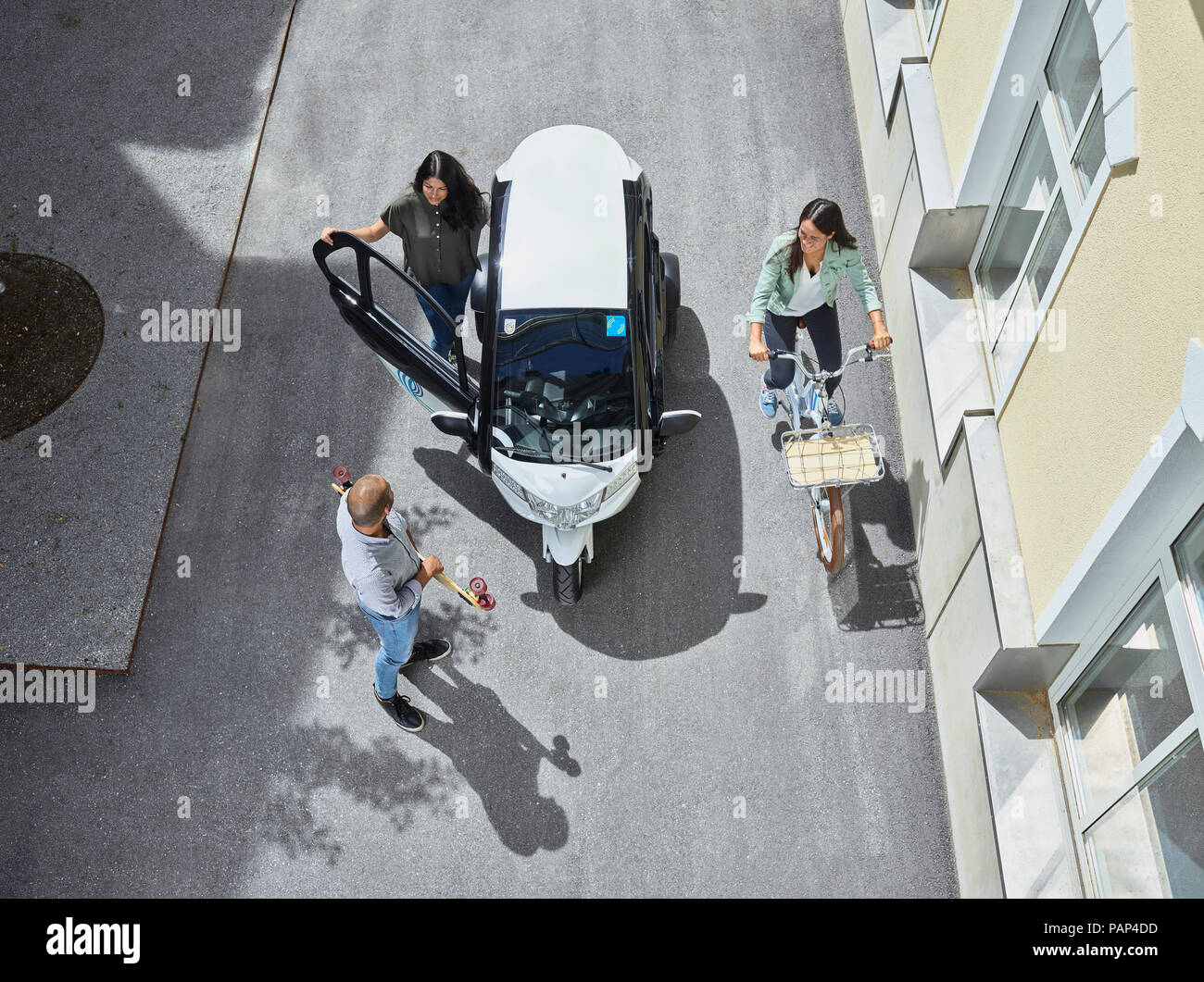 Tre persone con bolla elettrico auto, lo skateboard e la bicicletta Foto Stock