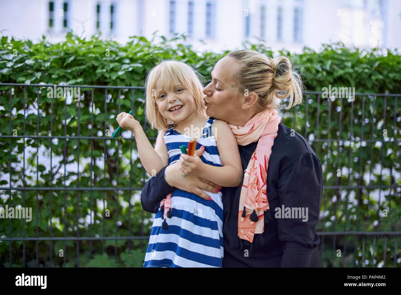 Ritratto di ridere bambina con la faccia dipinta in sua madre del braccio Foto Stock