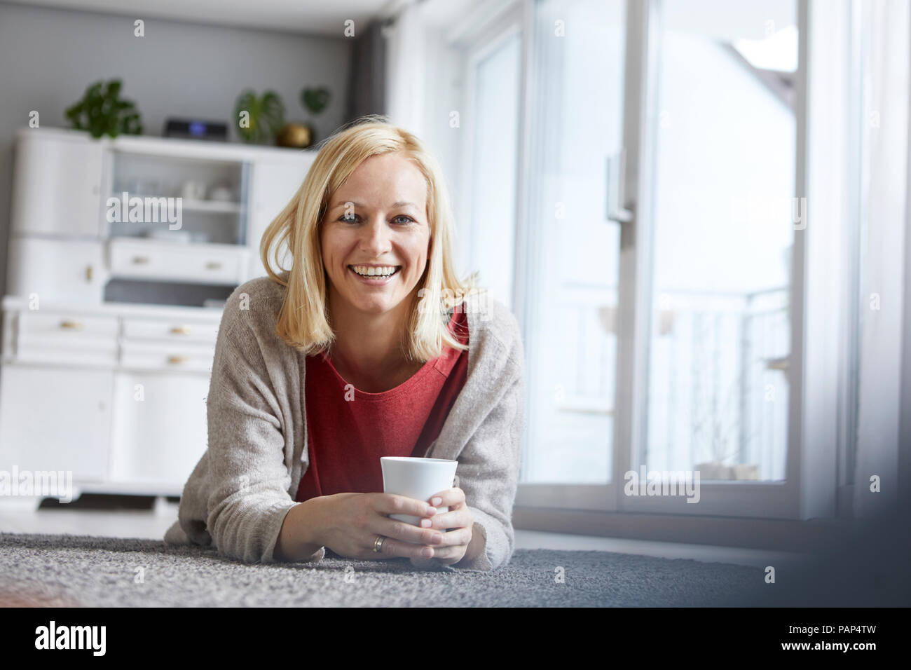 Donna felice in un momento di relax a casa, a bere caffè Foto Stock