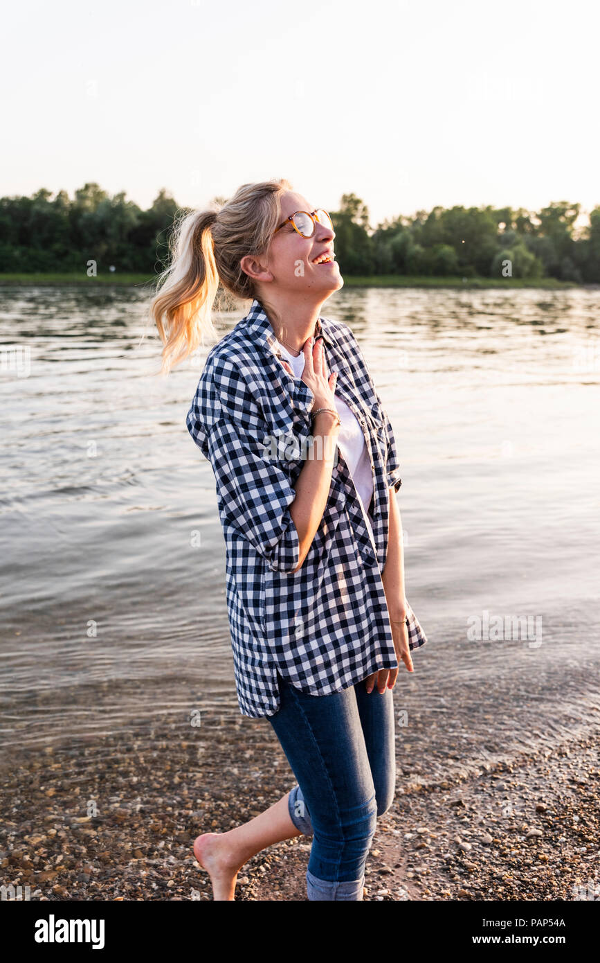 Ridendo giovane donna camminare sul lungofiume di sera Foto Stock