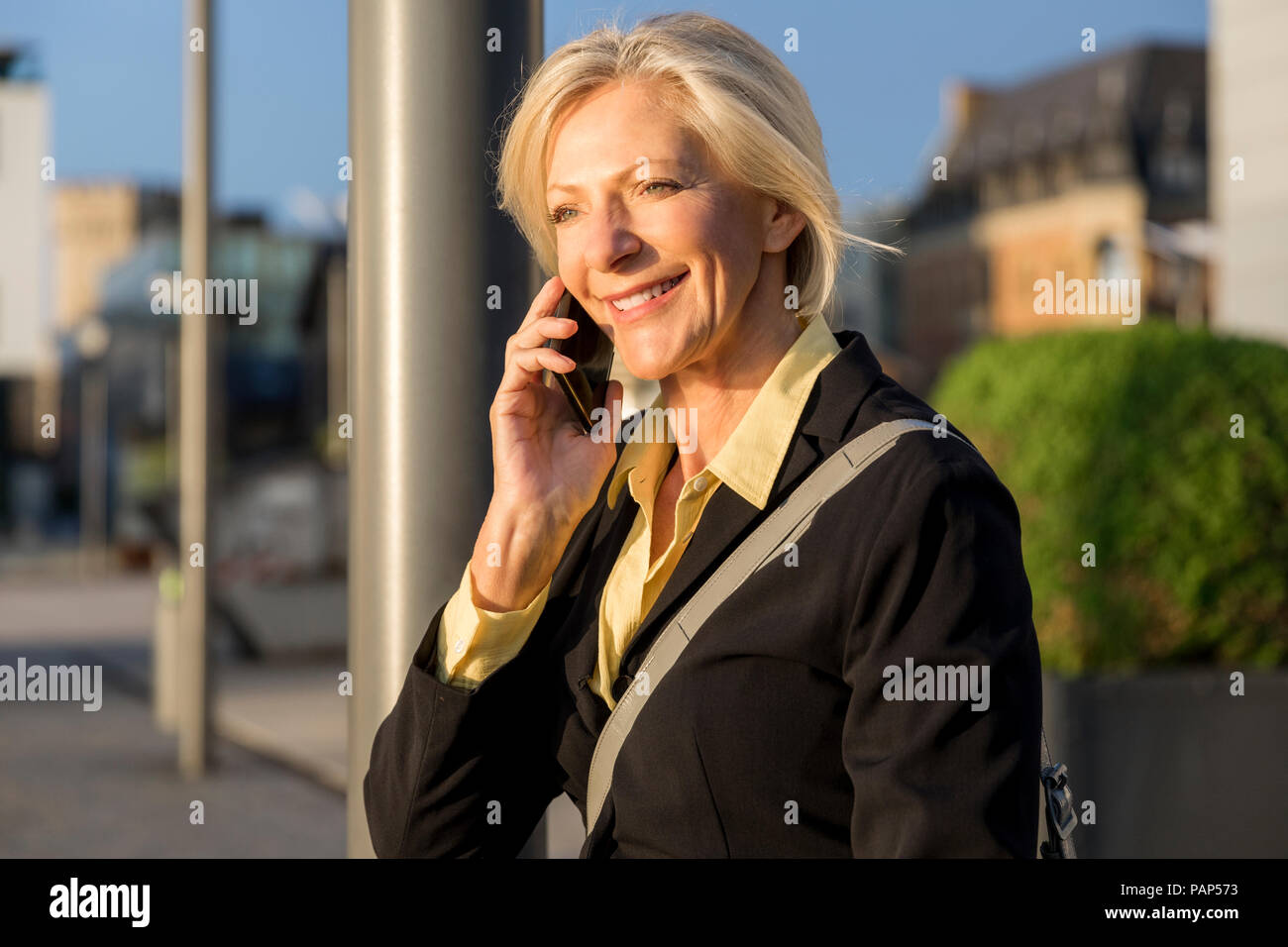 Sorridente senior imprenditrice sul cellulare all'aperto Foto Stock