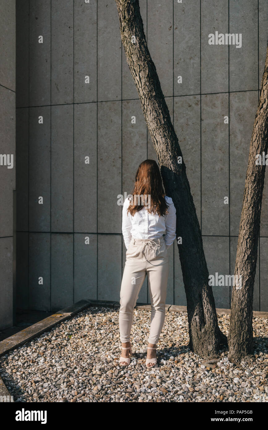 Giovane imprenditrice in piedi nel cortile, faccia coperte con i capelli Foto Stock