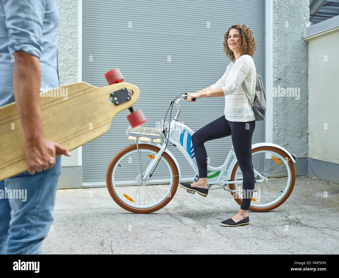 Uomo e donna con lo skateboard e la bicicletta Foto Stock