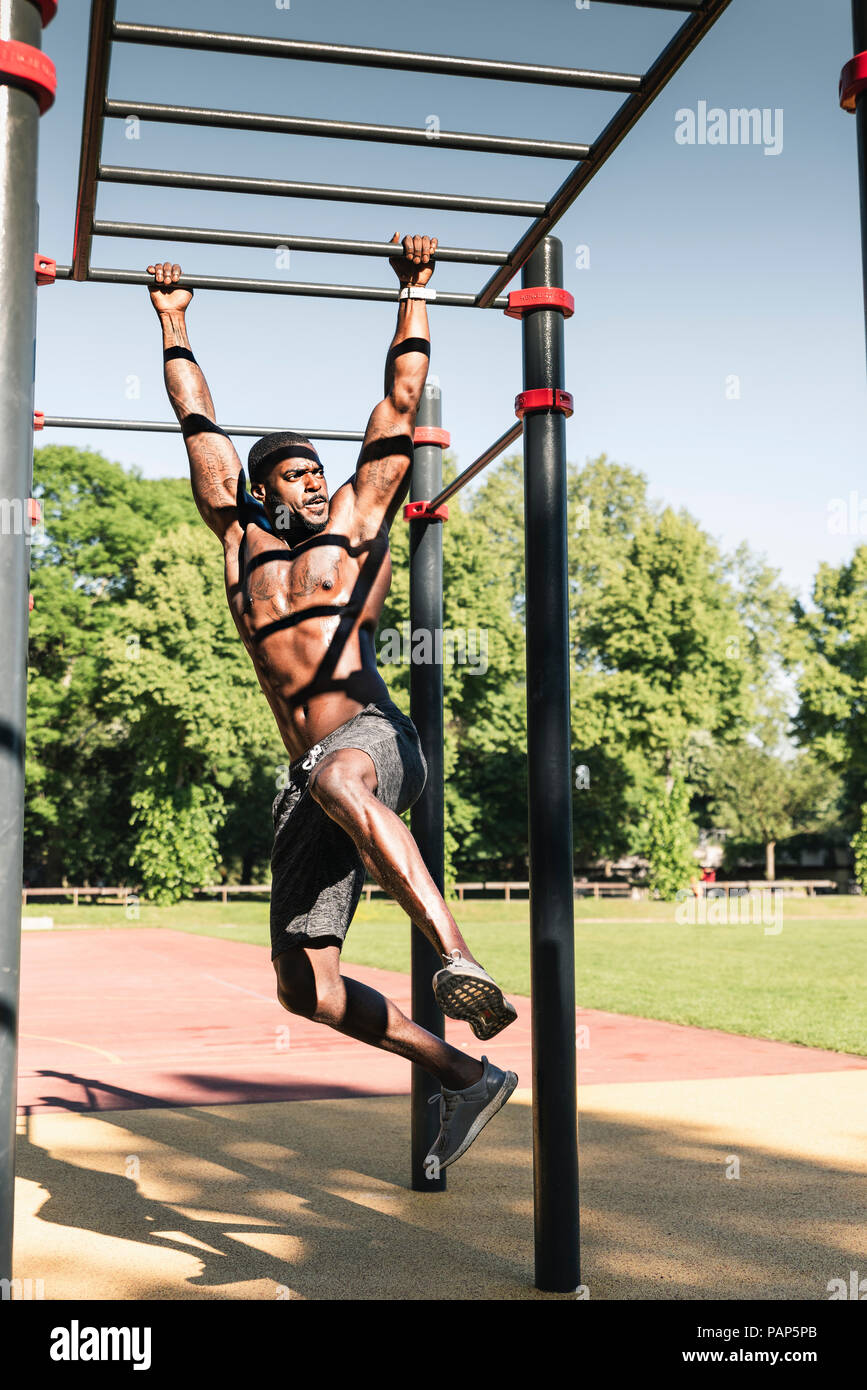 Muscoloso giovane esercitando su parcours bar Foto Stock