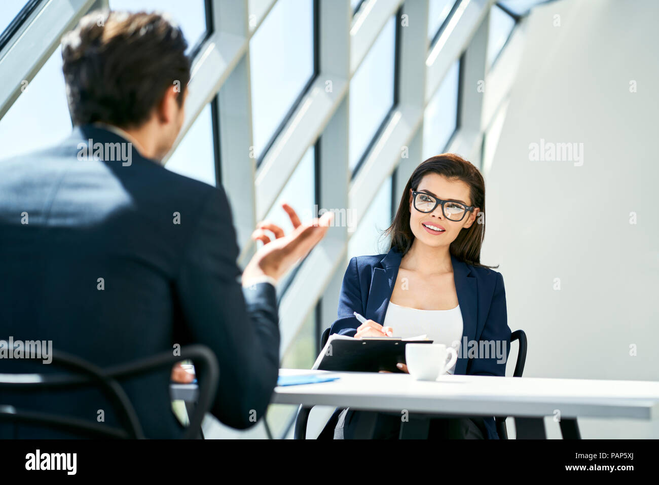 Imprenditrice e imprenditore parlando a scrivania in ufficio moderno Foto Stock