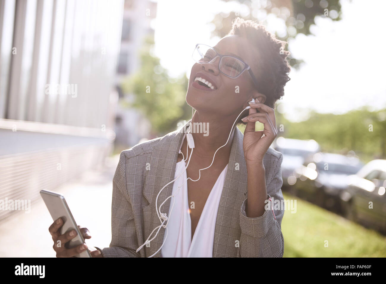 Ritratto di felice imprenditrice utilizza lo smartphone e gli auricolari Foto Stock