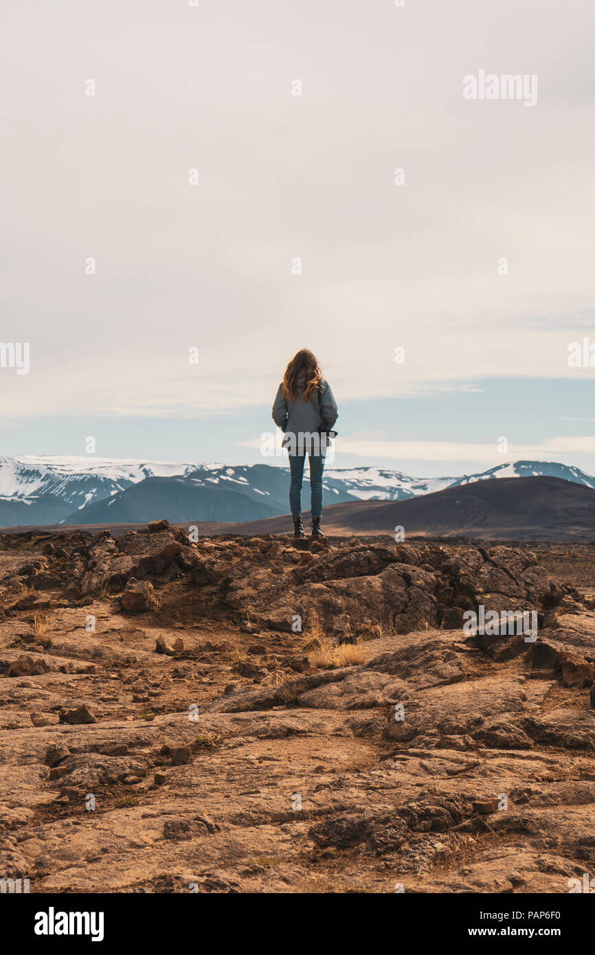 L'Islanda, femmina fotografo in piedi sulle rocce, vista posteriore Foto Stock