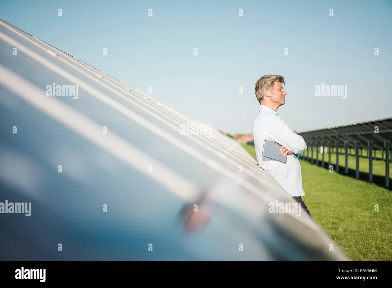 Imprenditore con auricolare wireless utilizzando tablet al parco solare Foto Stock