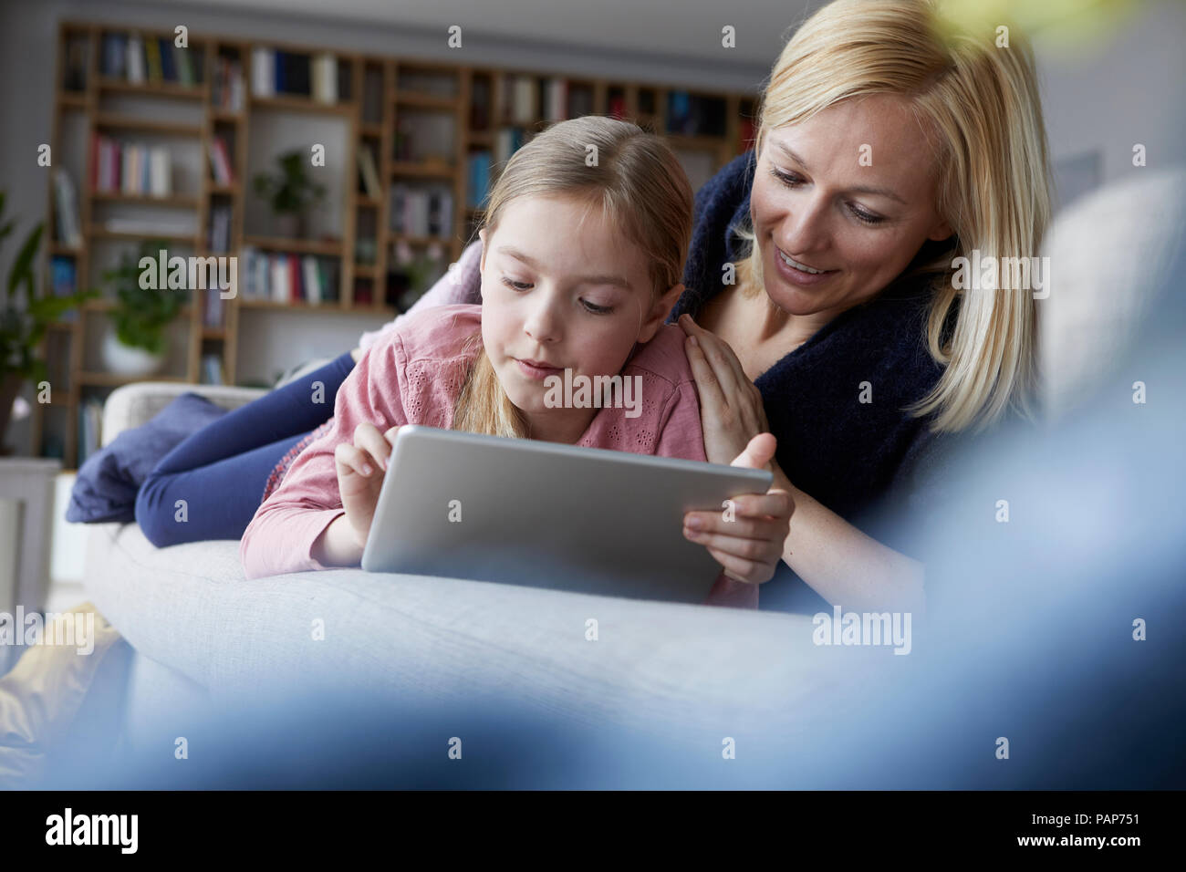 Madre e figlia sdraiato sul lettino, utilizzando tavoletta digitale Foto Stock