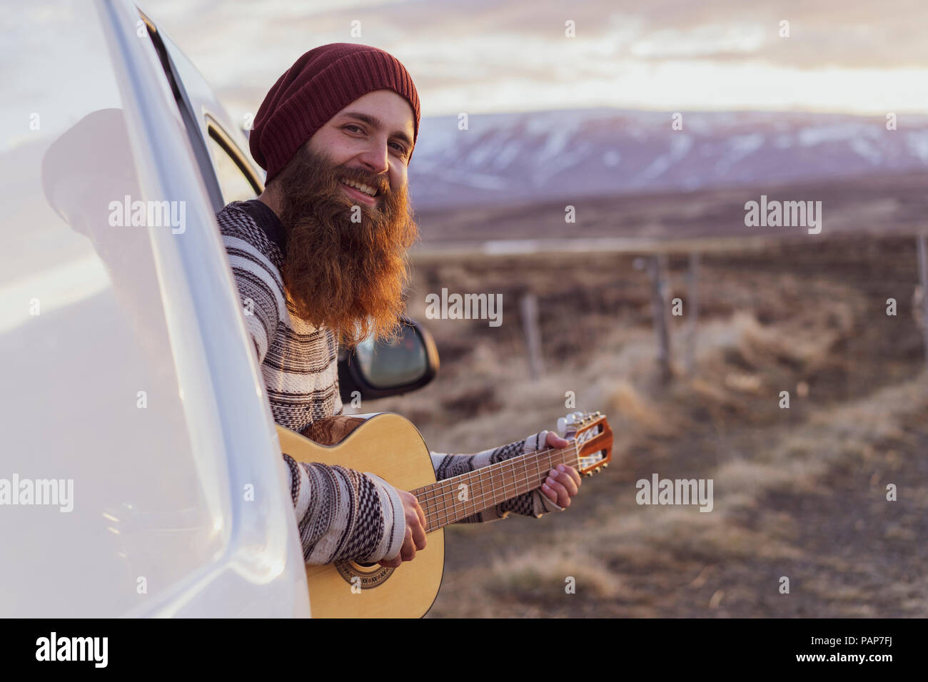 L'Islanda, il giovane uomo seduto in furgone e suonare la chitarra Foto Stock