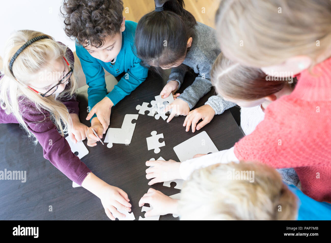Gli alunni la riproduzione di Jigsaw Puzzle nella scuola insieme Foto Stock