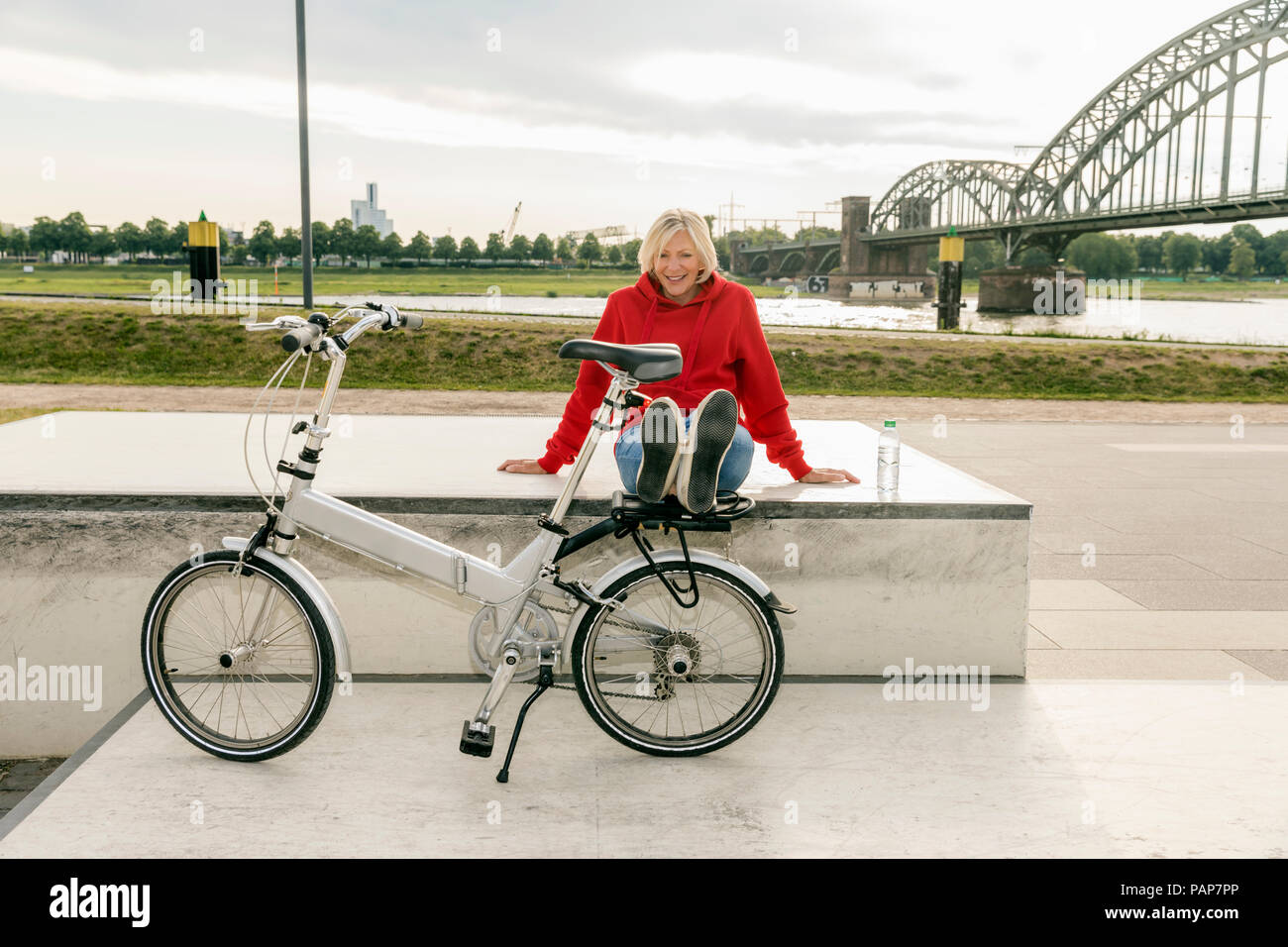Sorridente donna senior con city bike avente una pausa Foto Stock