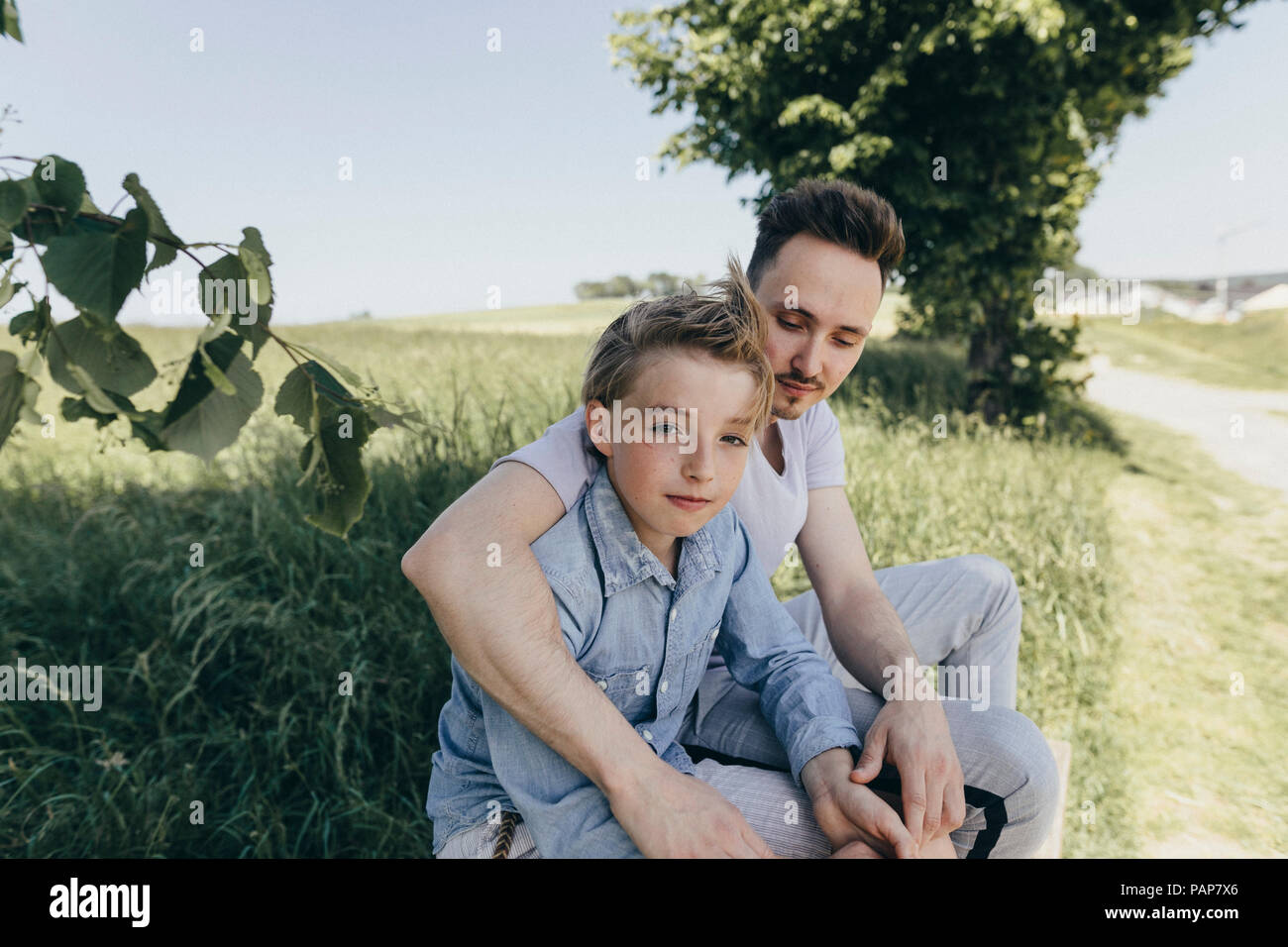 Ritratto di giovane uomo abbracciando ragazzo in un campo Foto Stock