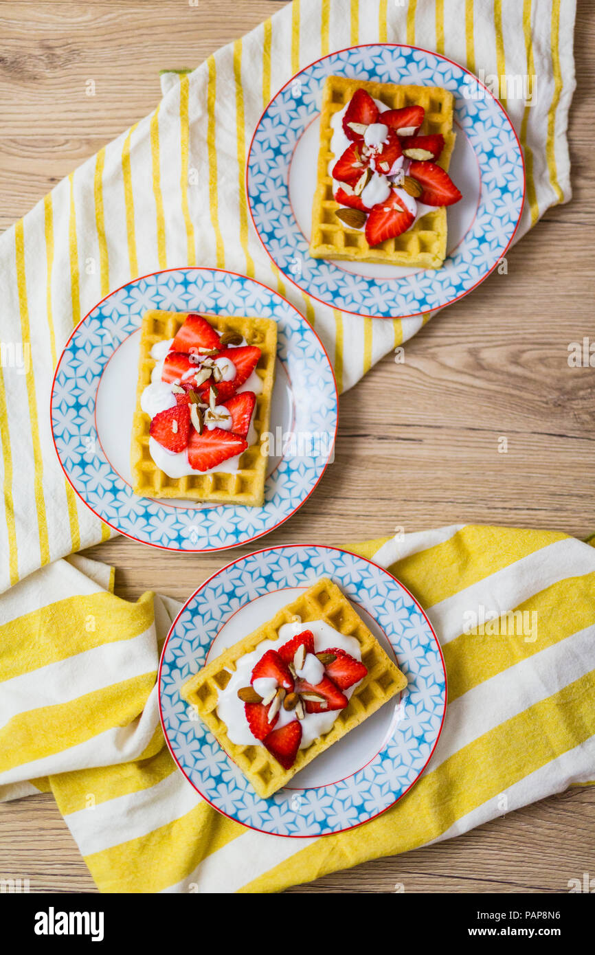 Tre piastre di cialde guarnito con fragole, yogurt greco e mandorle Foto Stock