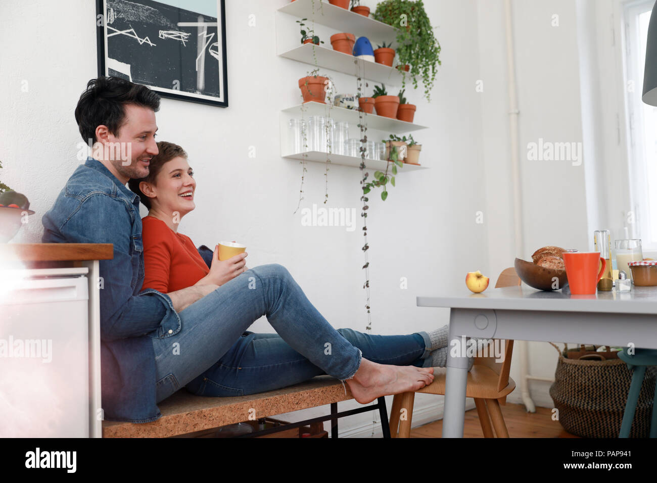 Felice coppia seduta in cucina, appoggiato contro l'altra Foto Stock