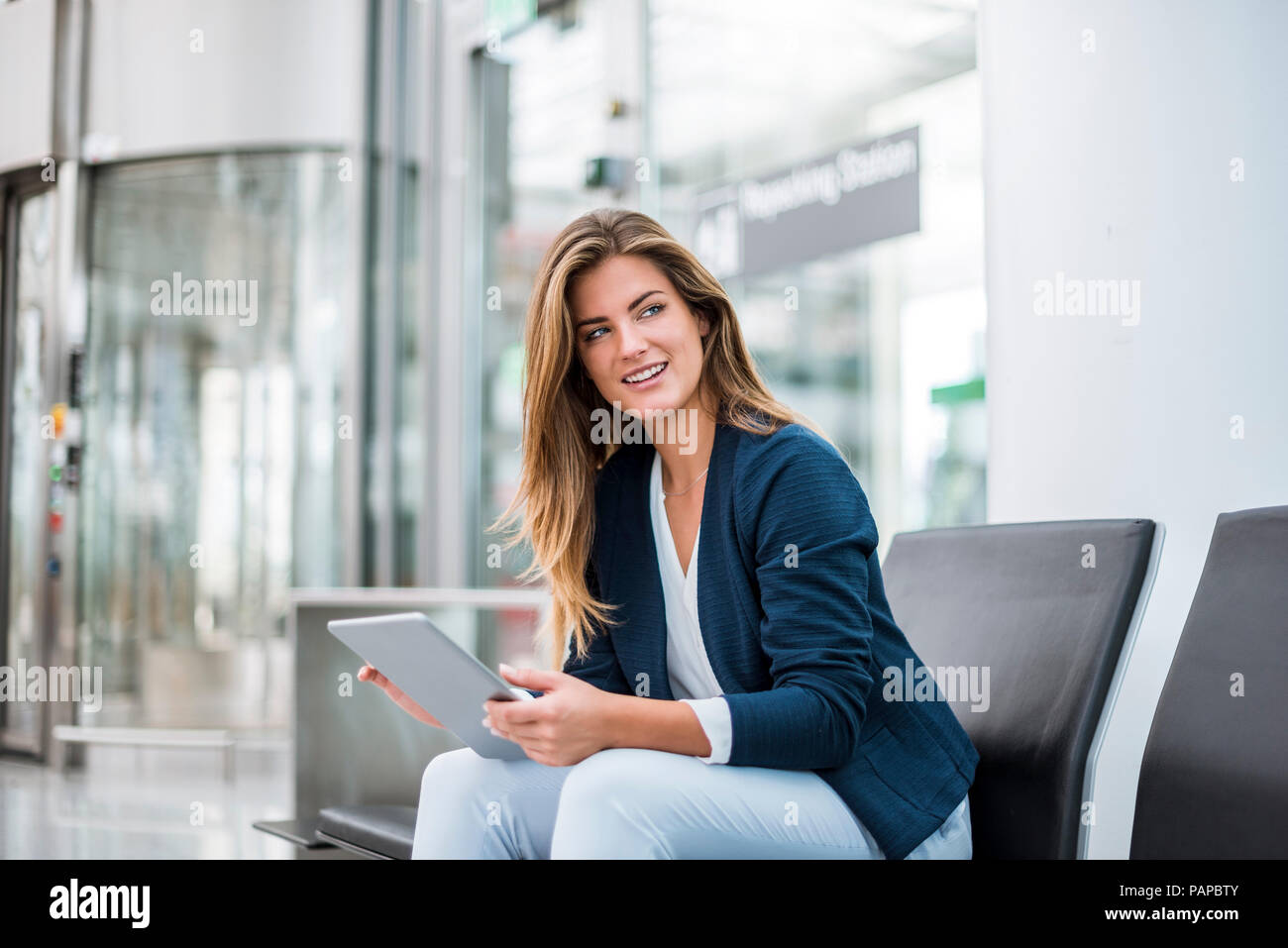 Giovane imprenditrice seduta a area di attesa utilizzando tablet Foto Stock