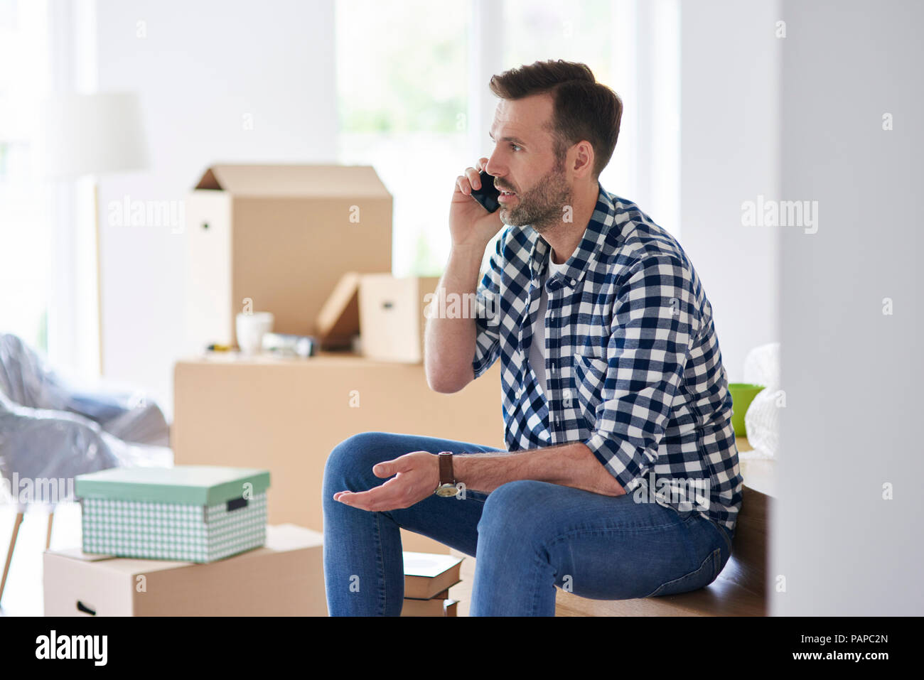 Grave uomo che si muove nel nuovo appartamento parlando al cellulare Foto Stock