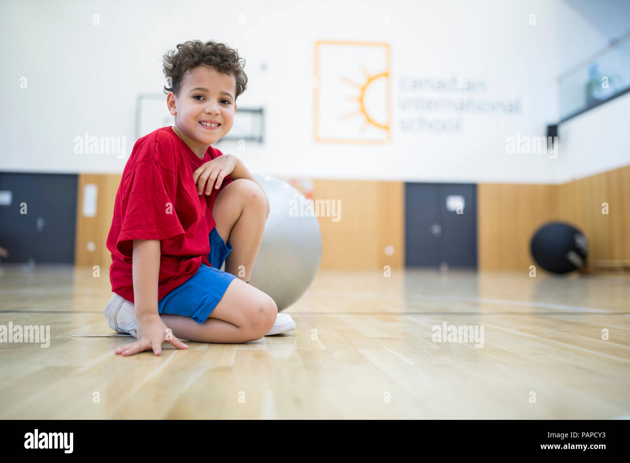 Ritratto di sorridere scolaro con palla in palestra classe Foto Stock