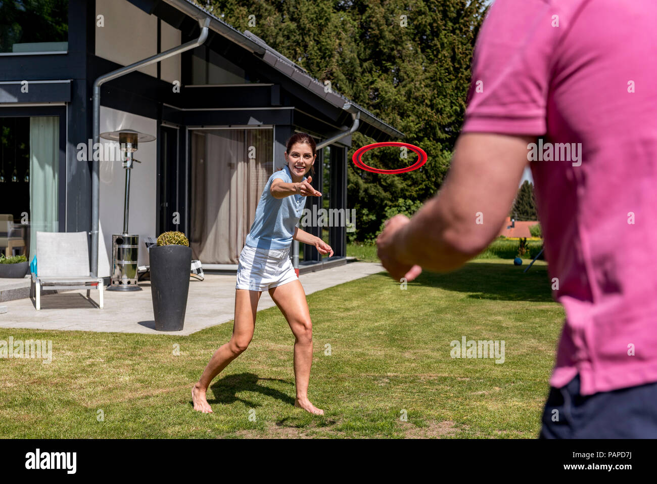 Coppia felice giocando con il flying disc nel giardino della loro casa Foto Stock