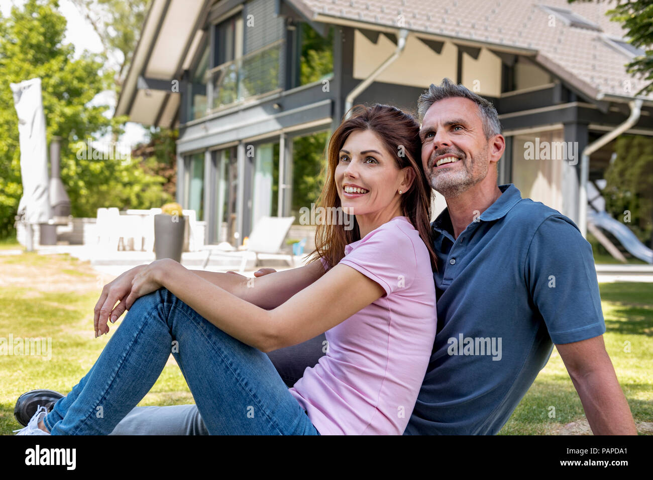 Felice coppia seduta nel giardino della loro casa Foto Stock