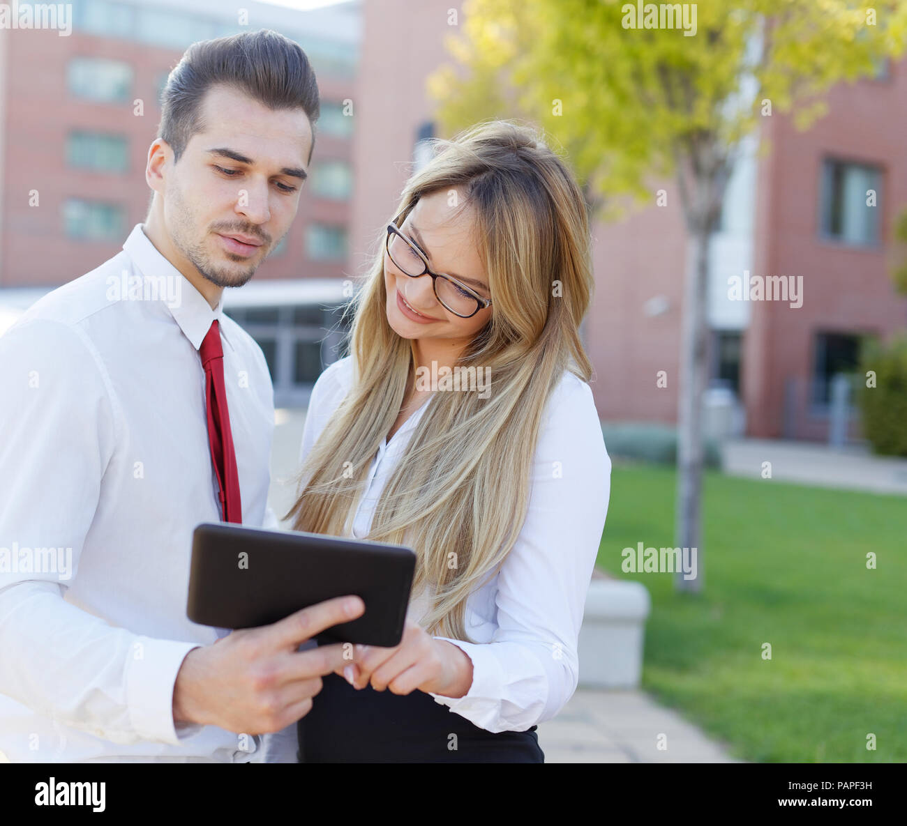 Alla moda di giovani imprenditori utilizzando tablet in città all'aperto, il quartiere finanziario Foto Stock