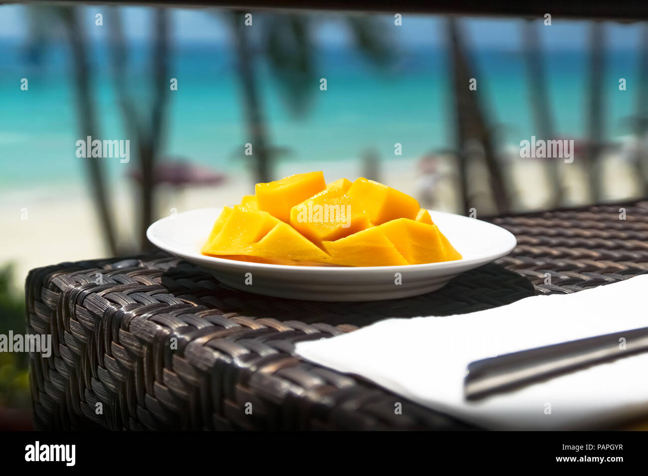 Freschi fette di mango sulla piastra al ristorante, con Tropical turchese del mare paesaggio - Spiaggia Bianca, Boracay - Filippine Foto Stock