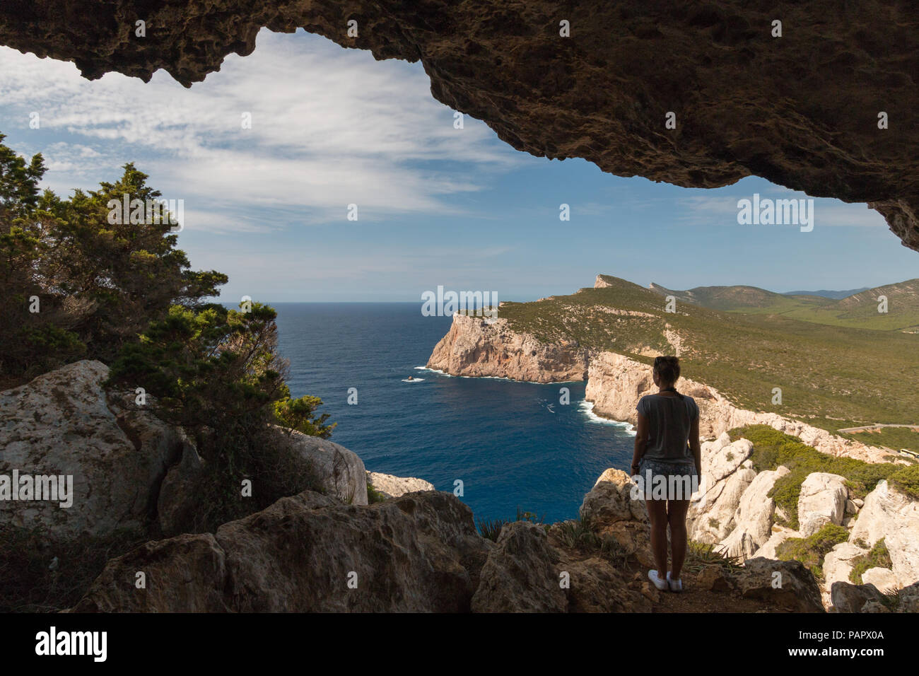 Donna che guarda al paesaggio dalla Grotta dei vasi rotti accanto a Capo Caccia sull'isola italiana di Sardegna Foto Stock