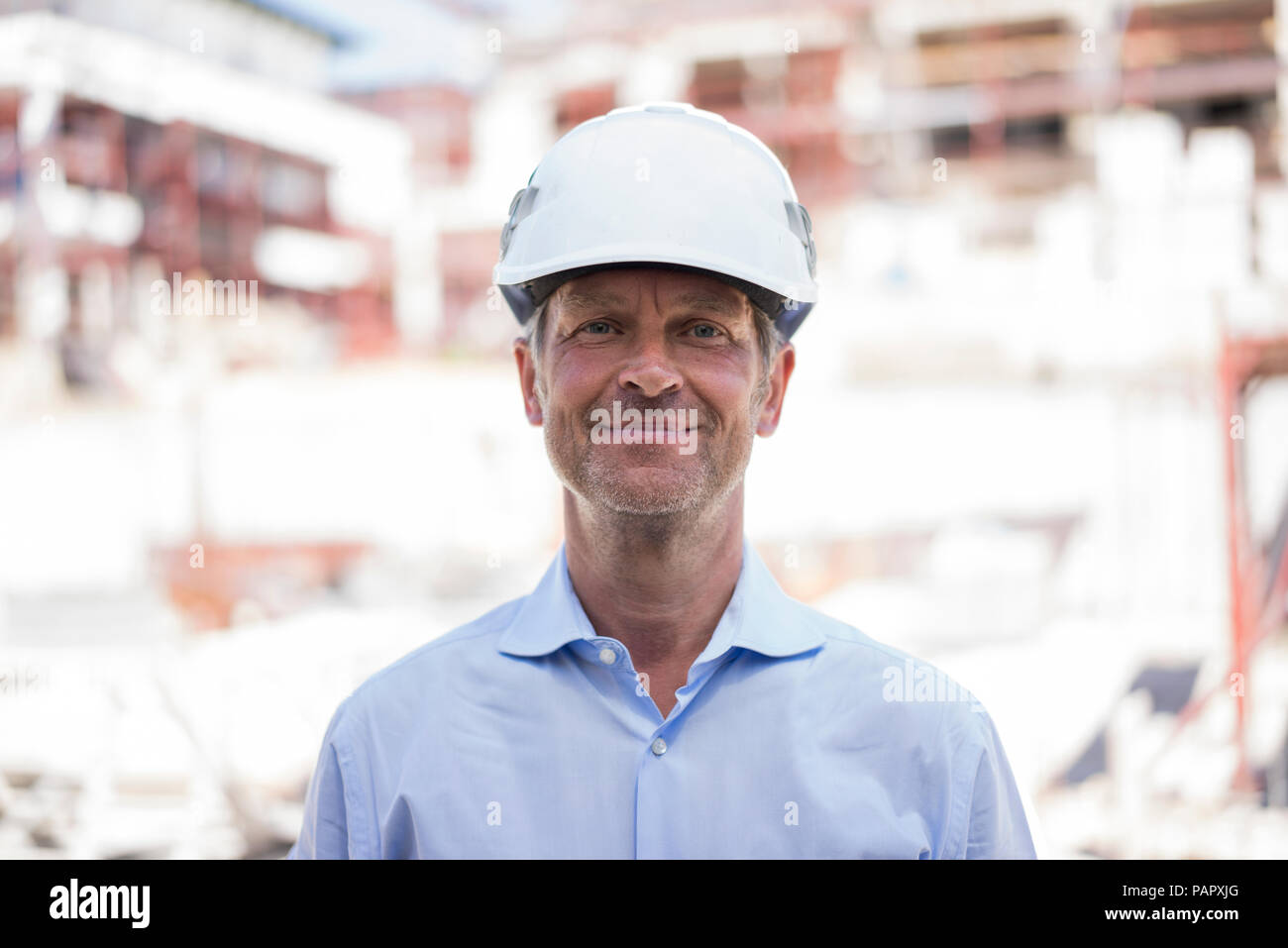 Ritratto di fiducioso uomo che indossa il casco sul sito in costruzione Foto Stock