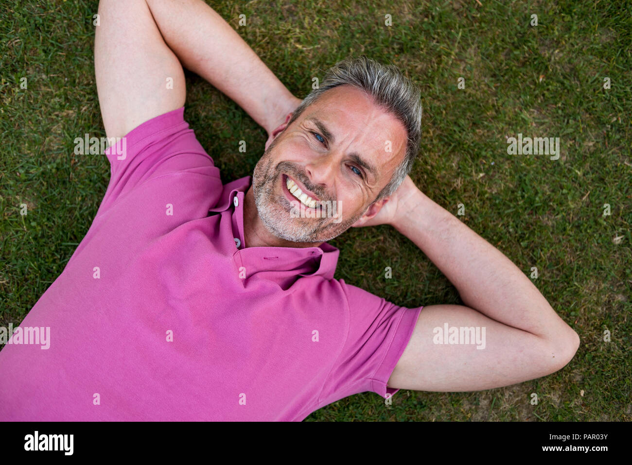 Ritratto di sorridere uomo maturo giacente in erba Foto Stock