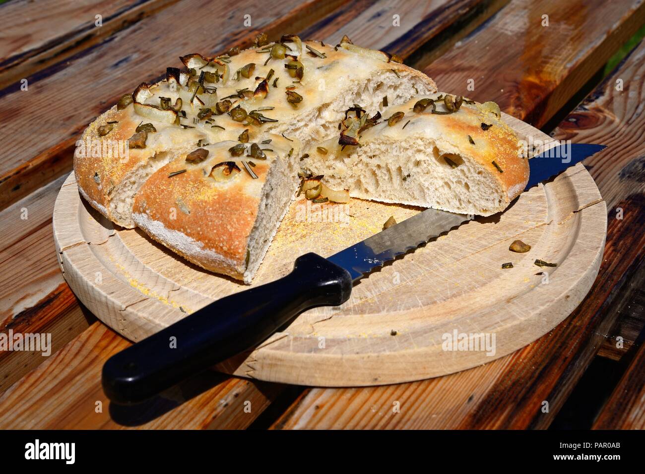 Casalingo italiano rosmarino, verde oliva e cipolla pane focaccia su una tavola di legno, England, Regno Unito, Europa. Foto Stock
