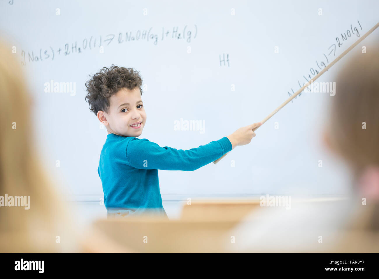 Scolaro spiegando formula a lavagna in classe Foto Stock