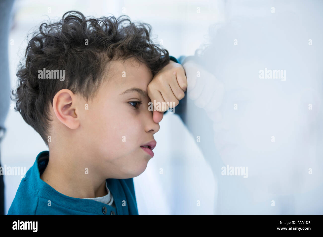 Sottolineato schoolboy appoggiata contro la lavagna in classe Foto Stock