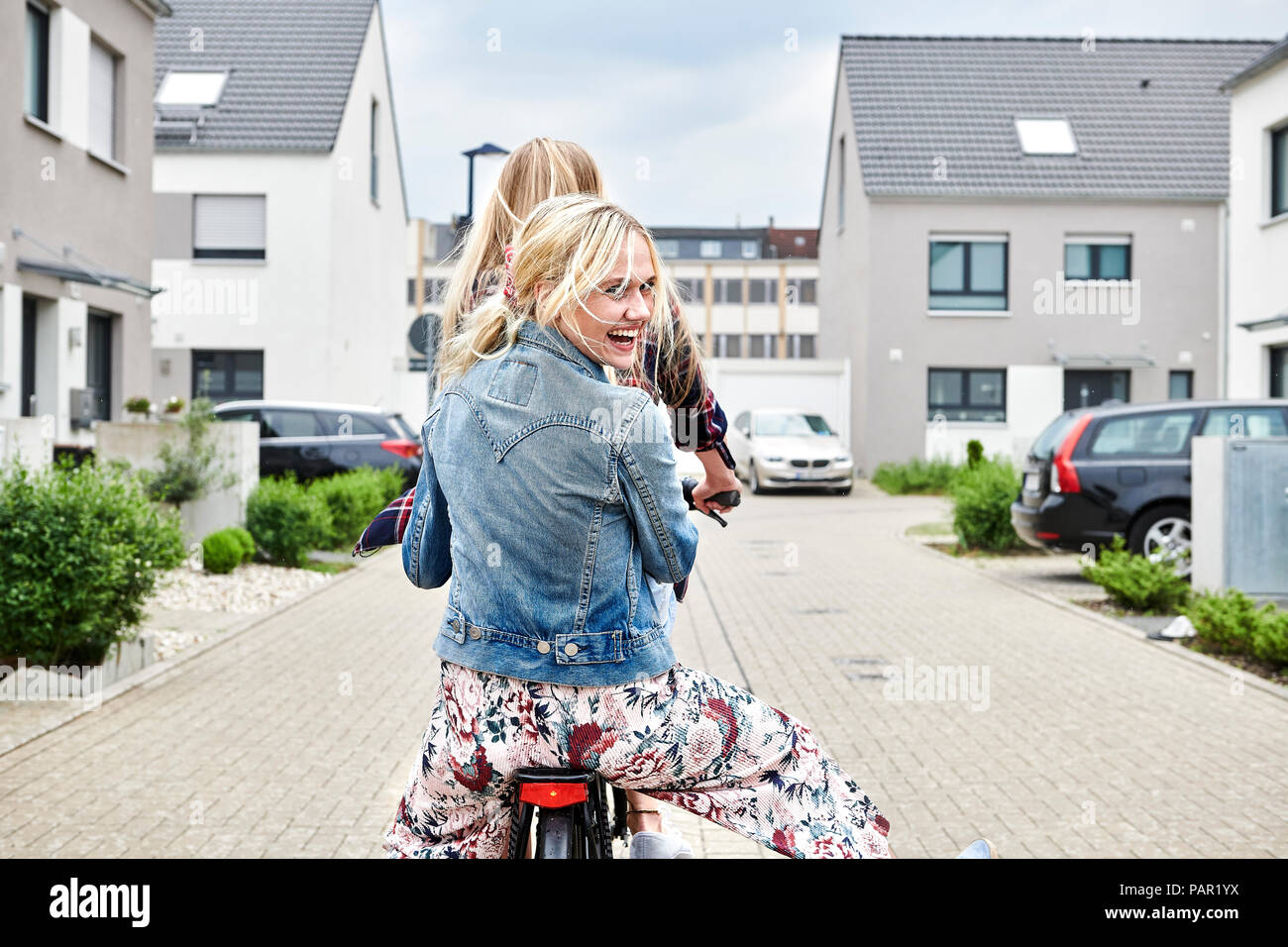 Due giovani felici donne equitazione Bicicletta insieme su una bicicletta Foto Stock
