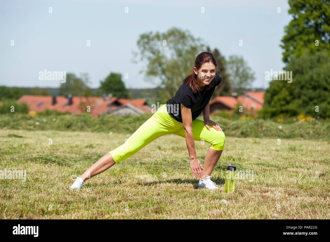 Donna facendo stretching excersice sul prato Foto Stock