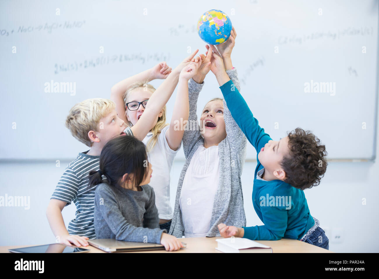 Felice gli alunni holding globe insieme in classe Foto Stock