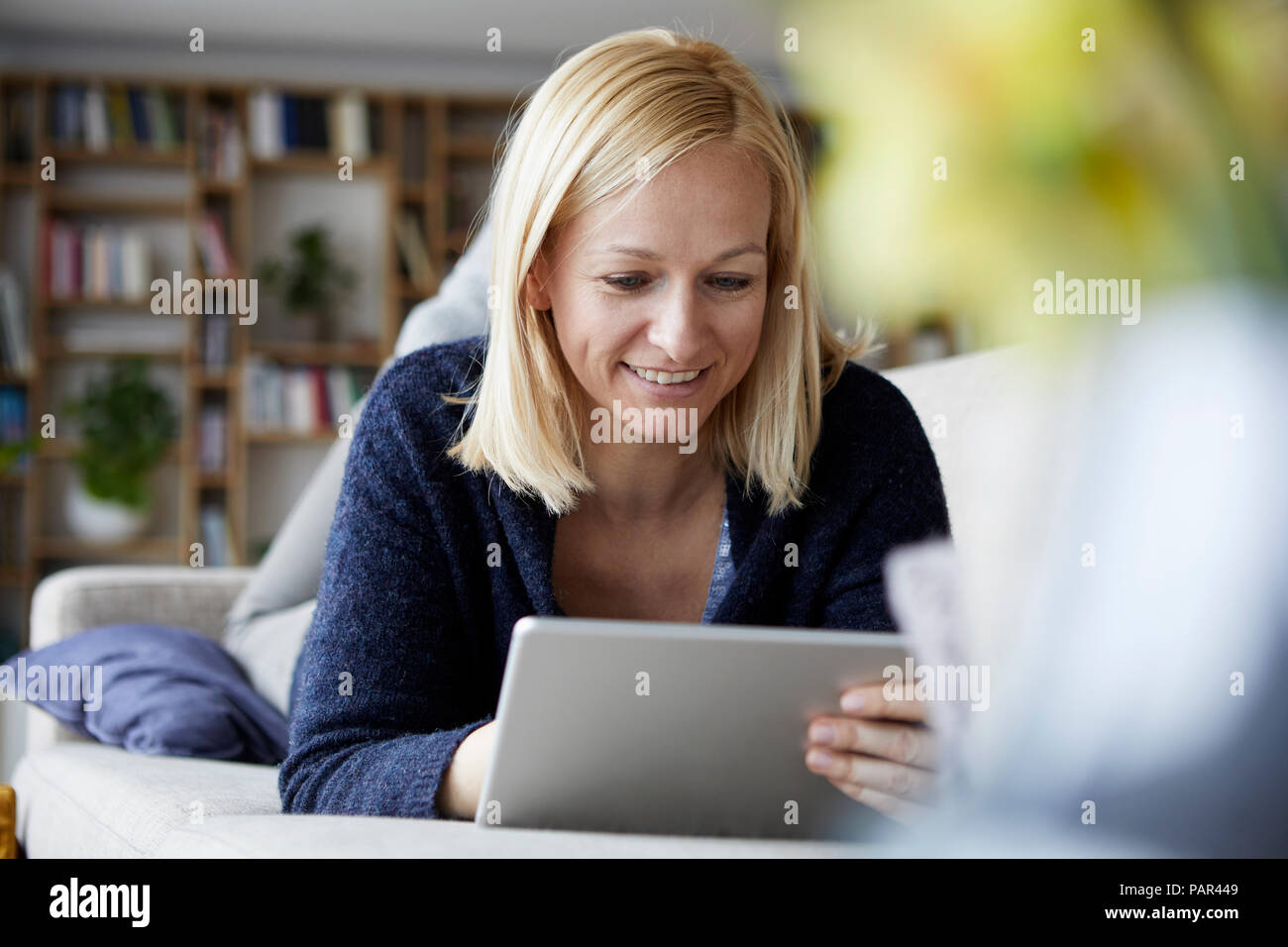 Donna che utilizza digitale compressa, rilassante sul lettino Foto Stock