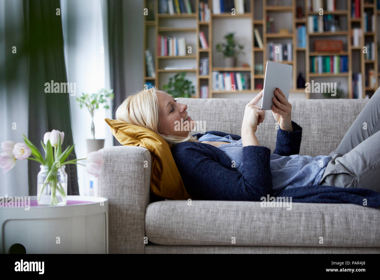 Donna che utilizza digitale compressa, rilassante sul lettino Foto Stock